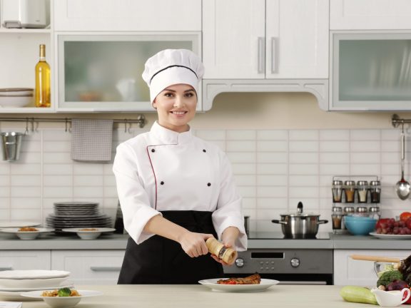 woman chef adding pepper