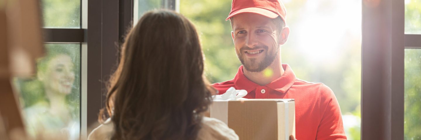 back view of woman receiving carton box from happy delivery man