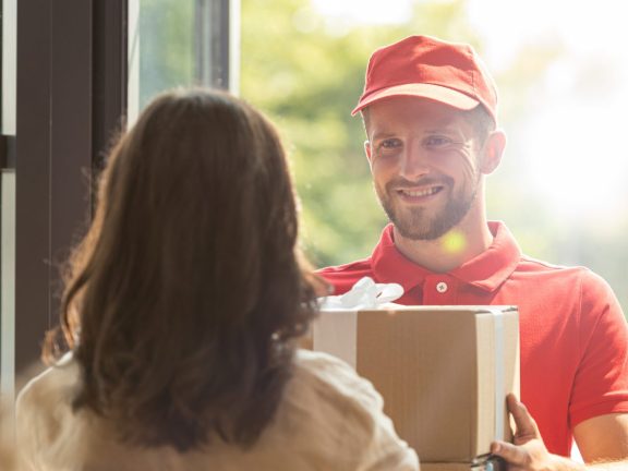 back view of woman receiving carton box from happy delivery man