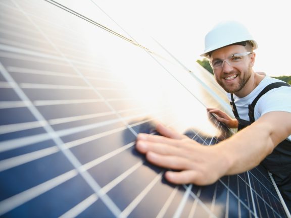 Man engineer in uniform working on solar panels power farm. Solar panel field. Clean energy production. Green energy