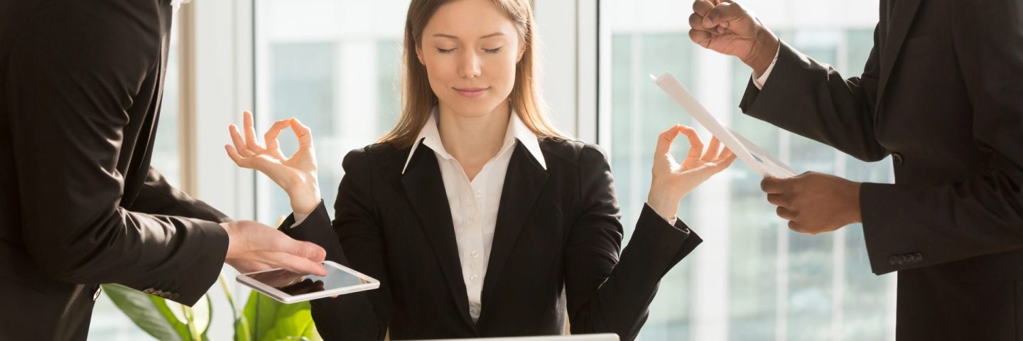 Beautiful businesswoman meditating at workplace, ignoring work a