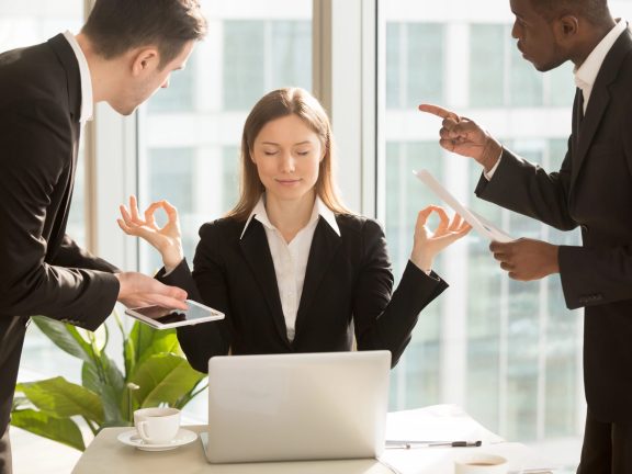 Beautiful businesswoman meditating at workplace, ignoring work a