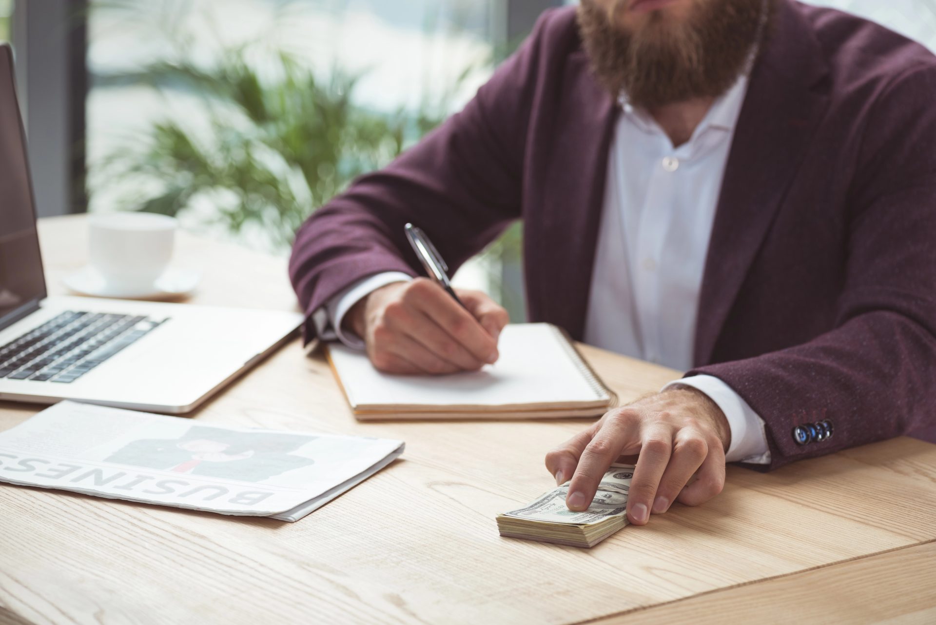 businessman writing and holding dollar