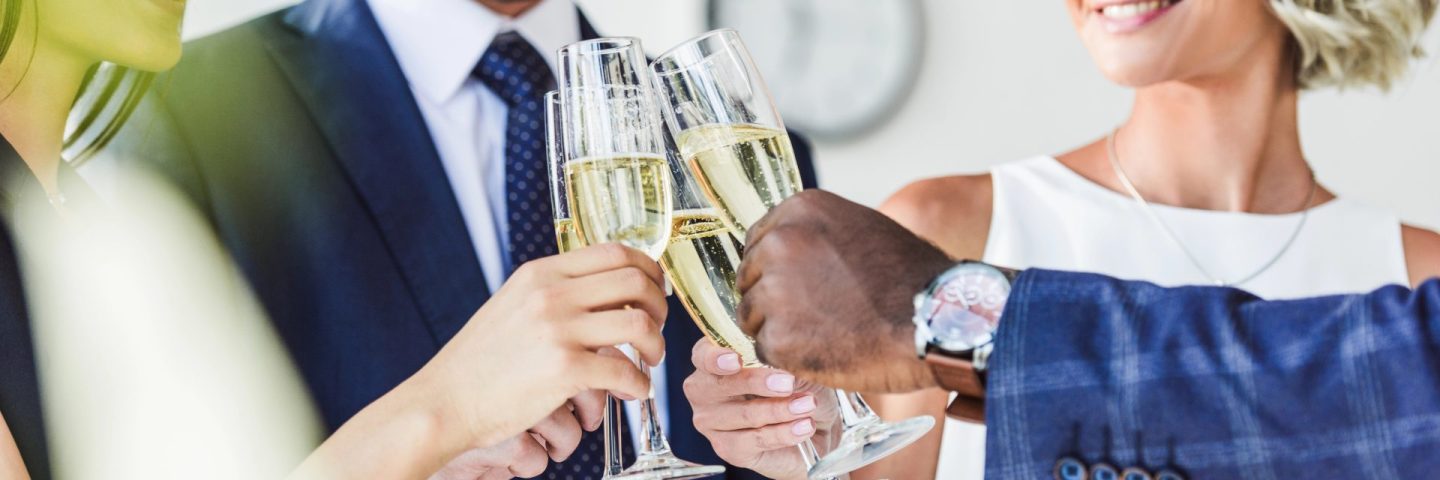 multiethnic businesspeople clinking with glasses of champagne in office