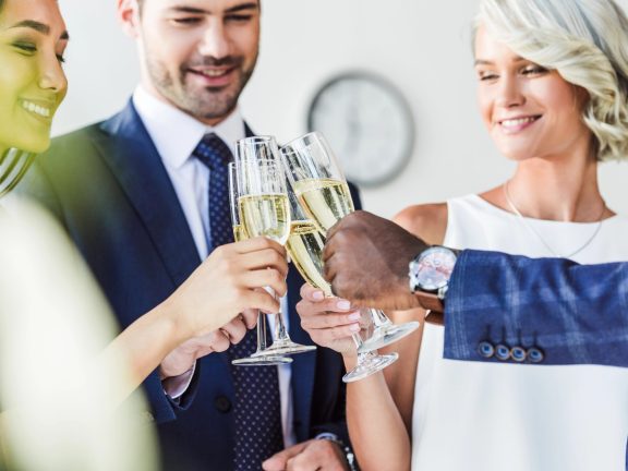 multiethnic businesspeople clinking with glasses of champagne in office