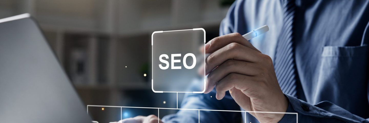 Hand of businessman holding a pen pointing to SEO Search Engine Optimization on laptop screen. Digital marketing process, Strategy,  Business Technology concept.