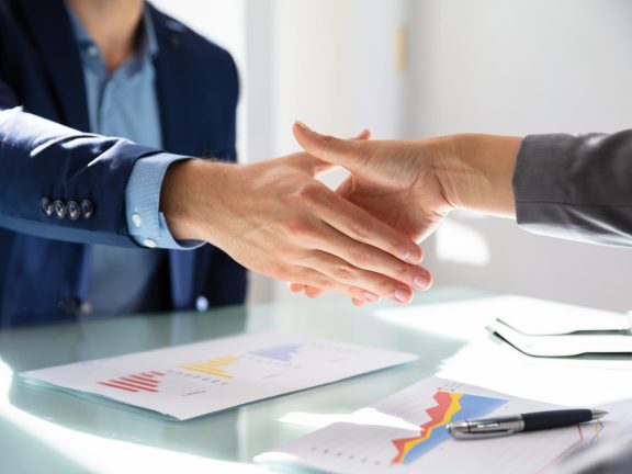 Elevated View Of Businessman Shaking Hands With His Partner Over Desk