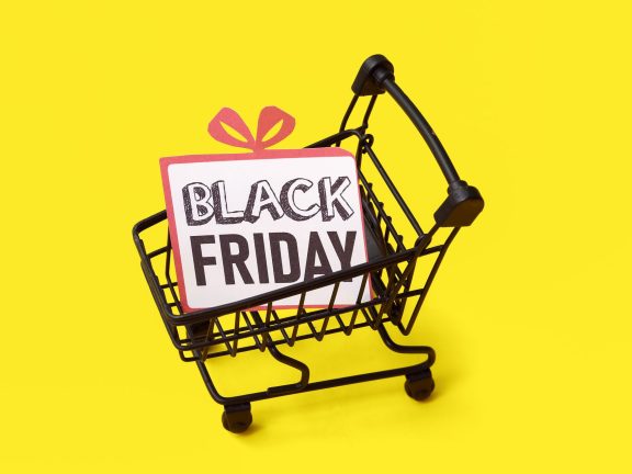 Greeting card with text BLACK FRIDAY in shopping cart on yellow background