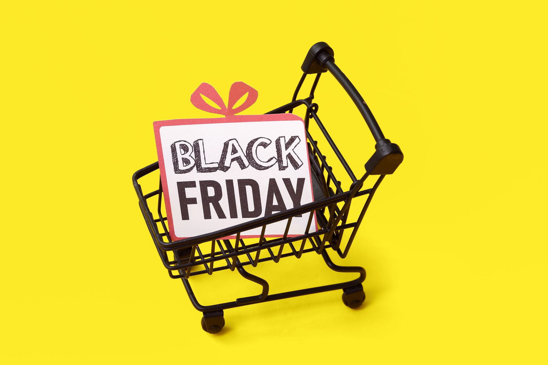 Greeting card with text BLACK FRIDAY in shopping cart on yellow background