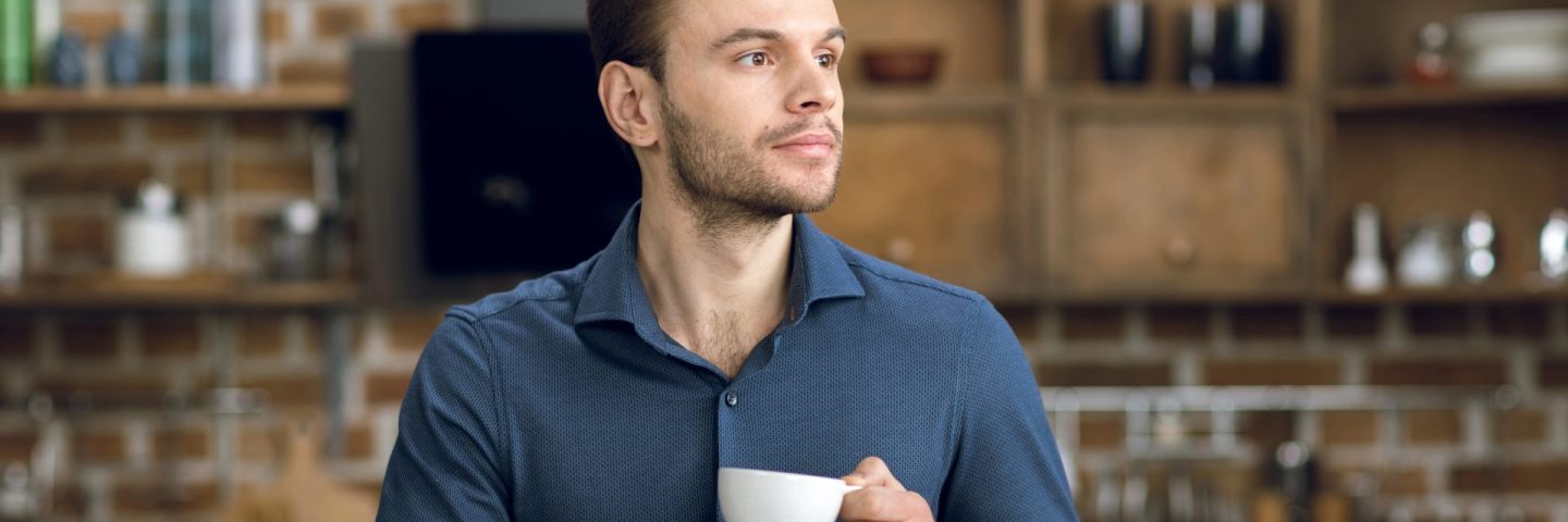 Man drinking coffee and using laptop