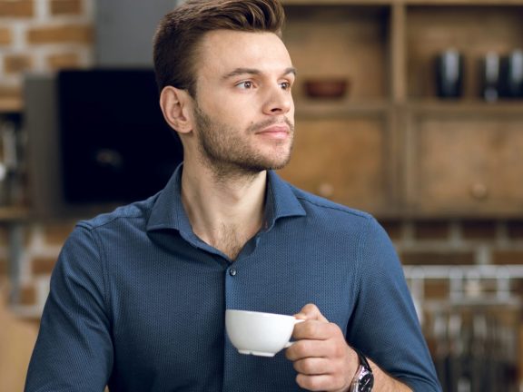 Man drinking coffee and using laptop