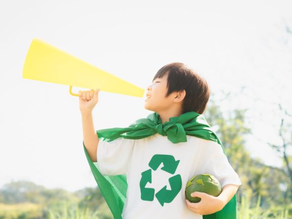 Young superhero boy with recycle symbol and cape make announcement with speaker on environmental awareness for eco-friendly waste recycling management as his mission to save Earth. Gyre