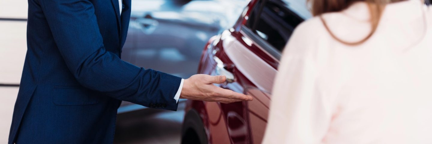 Manager inviting customer sit into car