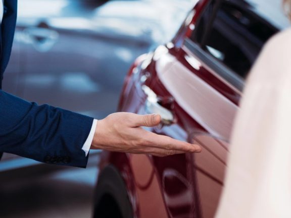 Manager inviting customer sit into car