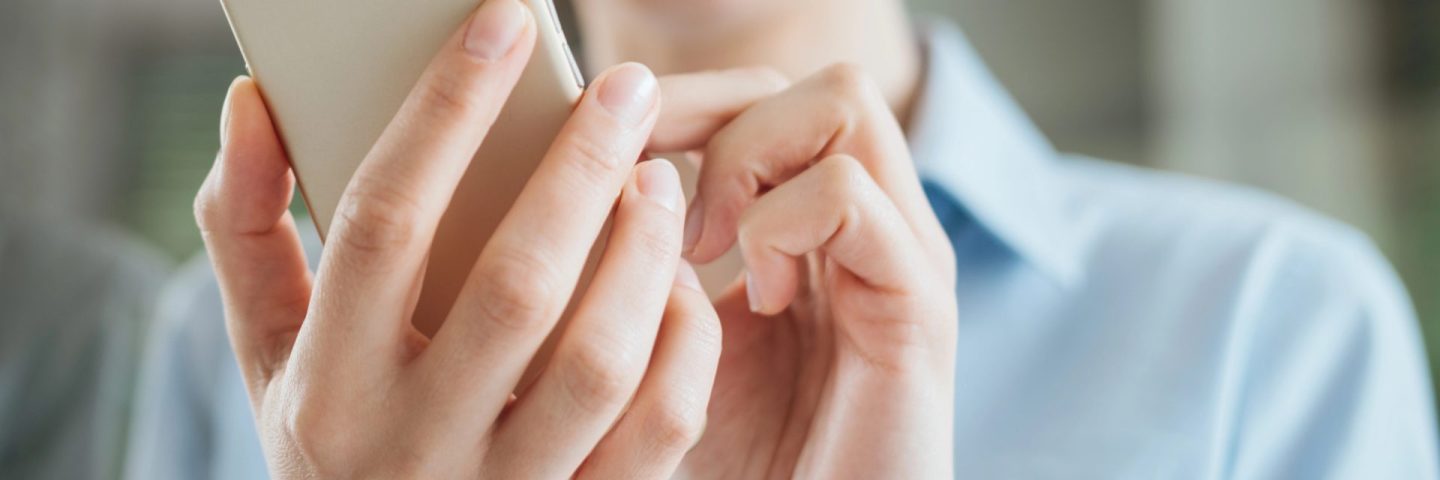 Woman using a smartphone and leaning on a window