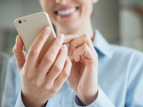 Woman using a smartphone and leaning on a window