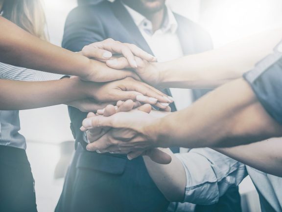 Close up view of young business people putting their hands together. Stack of hands. Unity and teamwork concept.
