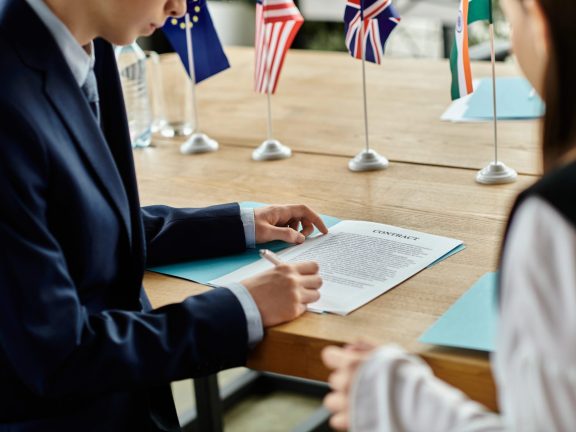 Two teenagers participate in a UN Model conference, signing a contract.