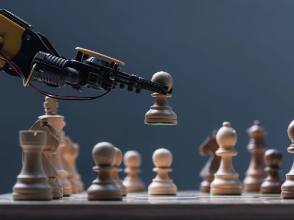 Robot moving chess pieces on chessboard, close up