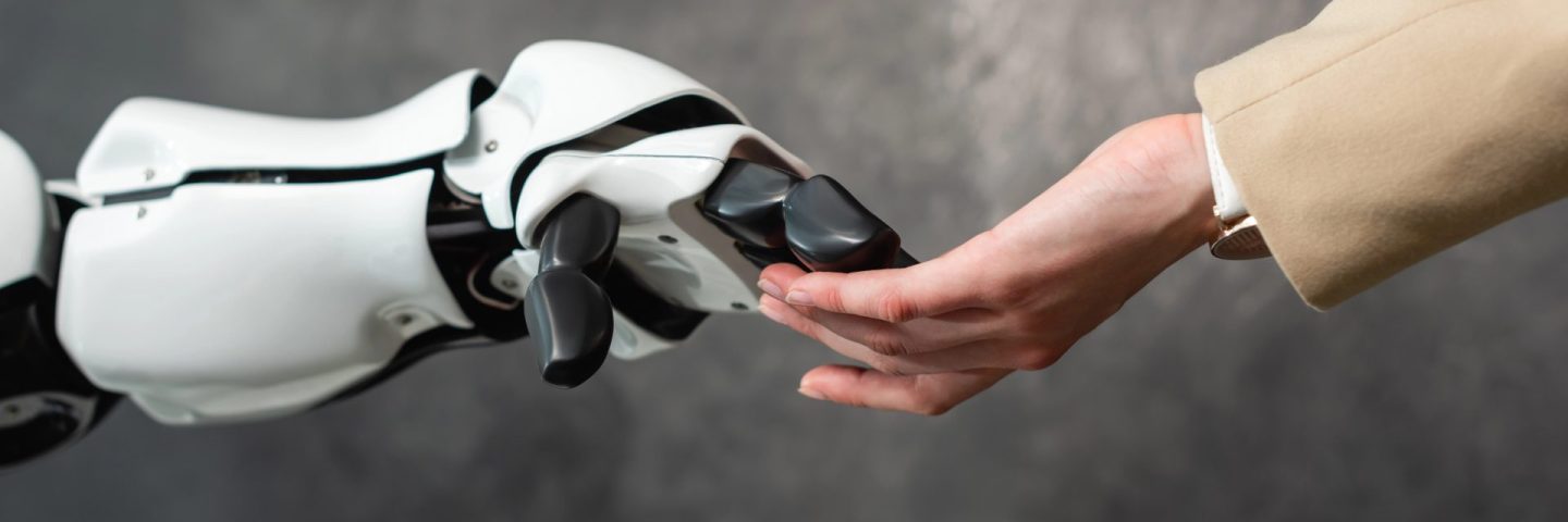 cropped view of businesswoman touching hand of humanoid robot