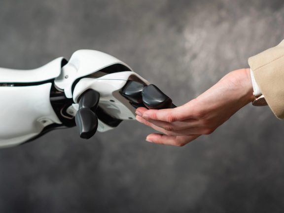 cropped view of businesswoman touching hand of humanoid robot