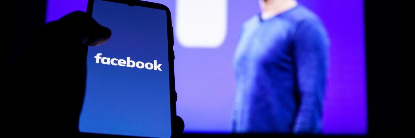 Facebook logo on screen and Mark Zuckerberg is a Chief Executive Officer of Facebook in background