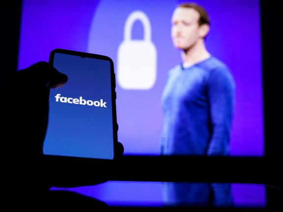 Facebook logo on screen and Mark Zuckerberg is a Chief Executive Officer of Facebook in background