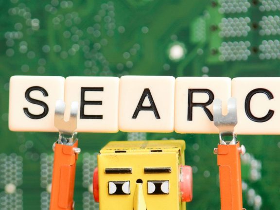Search engine robot is looking for the best online website metaphor with toy robot on computer curuit board