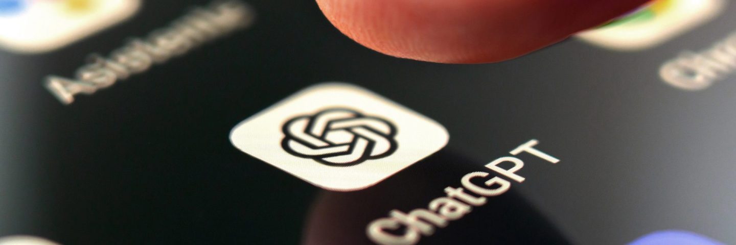 Oviedo, Spain - December, 13, 2023: ChatGPT app icon on smartphone screen with pushing finger. Artificial intelligence chatbot service on mobile phone. Macro shot