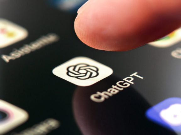 Oviedo, Spain - December, 13, 2023: ChatGPT app icon on smartphone screen with pushing finger. Artificial intelligence chatbot service on mobile phone. Macro shot