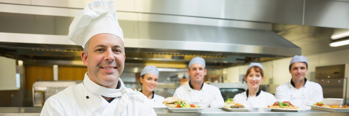 Proud mature head chef posing in a modern kitchen