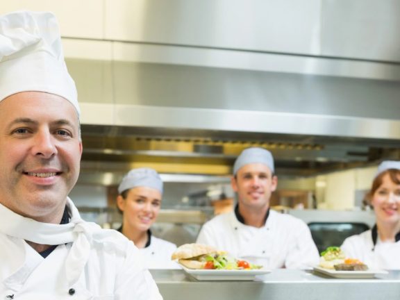 Proud mature head chef posing in a modern kitchen