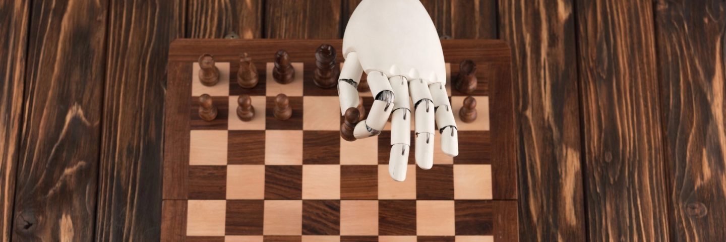 cropped shot of robot playing chess with human on wooden surface