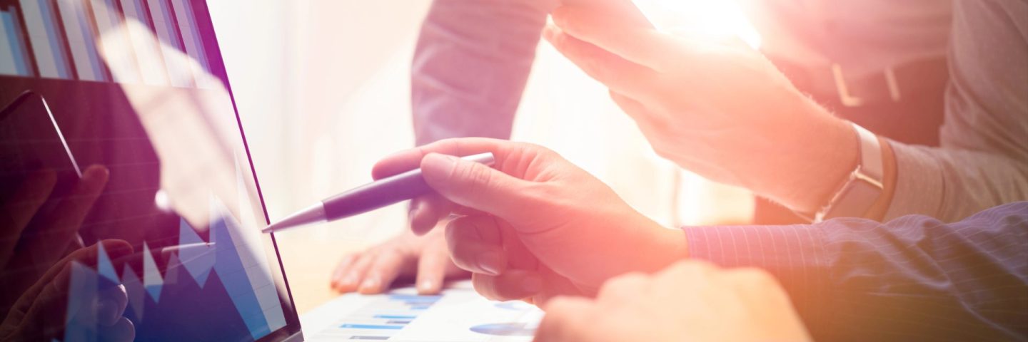 Two colleagues working on new global financial strategy plan using laptop and smartphone.Modern business team innovation concept.Project meeting at office with virtual graph and chart data interface