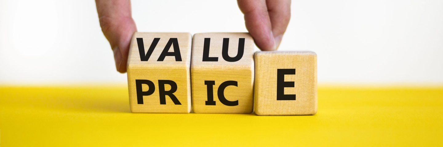 Value and price symbol. Businessman turns wooden cubes and changes the word price to value or vice versa. Beautiful yellow table, white background, copy space. Business value and price concept.