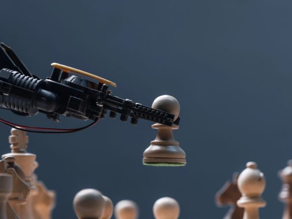 Robot moving chess pieces on chessboard, close up
