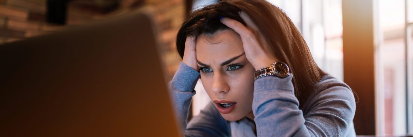 Frustrated worried young woman looks at laptop upset by bad news, teenager feels shocked afraid reading negative bullying message, stressed girl troubled with problem online or email notification.
