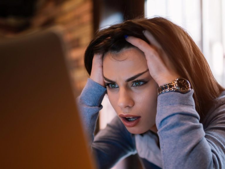 Frustrated worried young woman looks at laptop upset by bad news, teenager feels shocked afraid reading negative bullying message, stressed girl troubled with problem online or email notification.