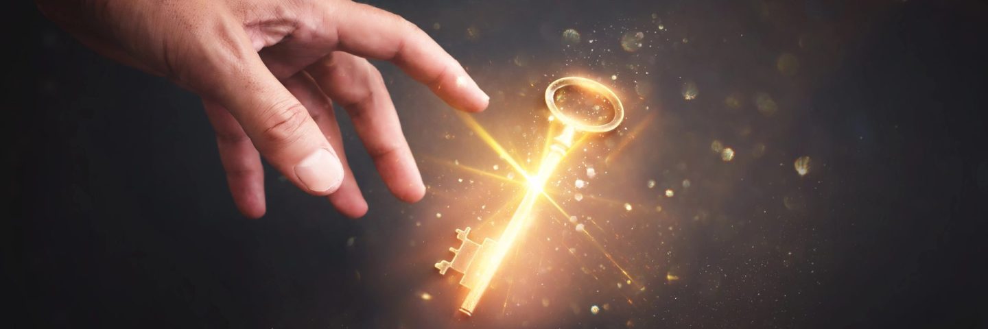Male hand holding golden key with glowing light. Concept of success and wealth