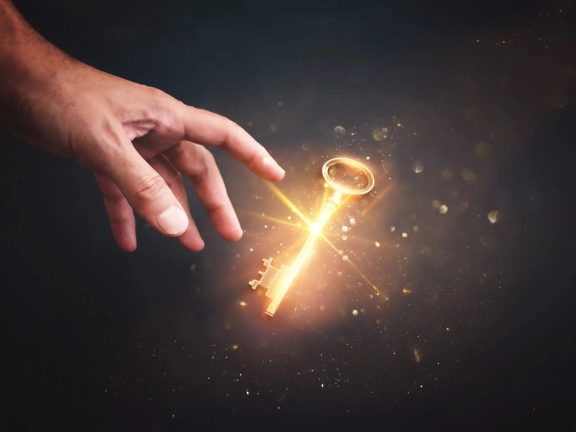 Male hand holding golden key with glowing light. Concept of success and wealth