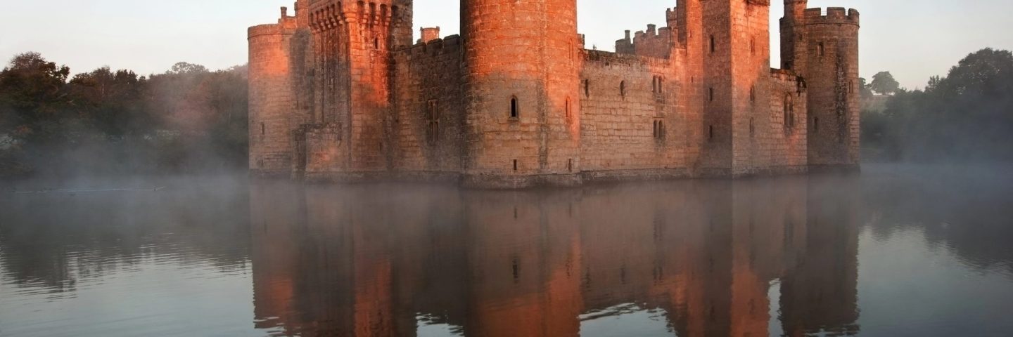 Stunning moat and castle in Autumn Fall sunrise with mist over m
