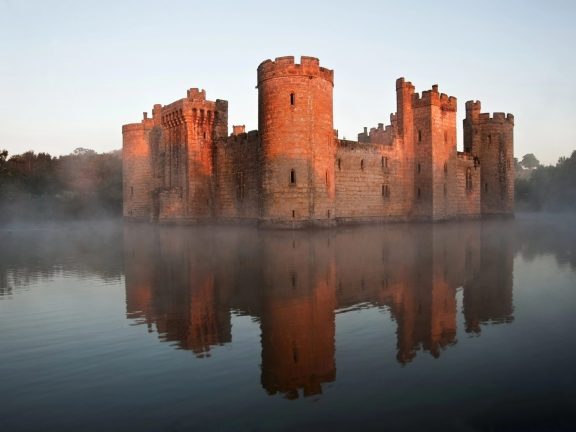 Stunning moat and castle in Autumn Fall sunrise with mist over m