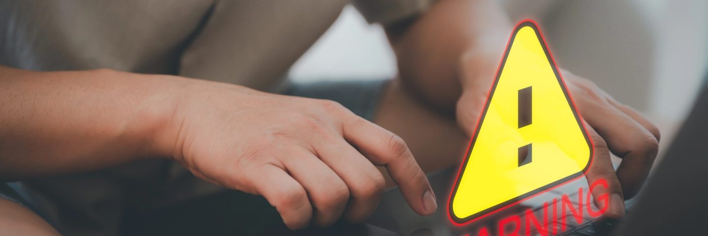 User man using a computer laptop with triangle caution warning sign for notification error. Concept technology of computer virus detected, personal data protection, network security and maintenance.