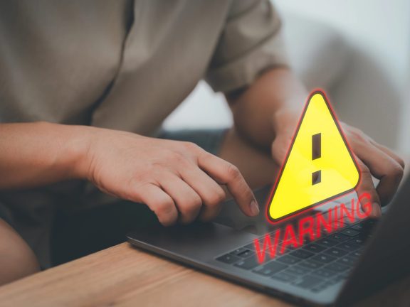 User man using a computer laptop with triangle caution warning sign for notification error. Concept technology of computer virus detected, personal data protection, network security and maintenance.