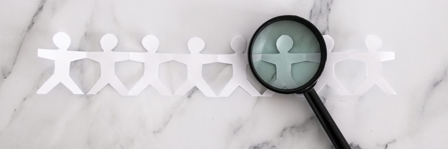 staff shortages and hiring personnel conceptual image, paper people chain with magnifying glass analysing them