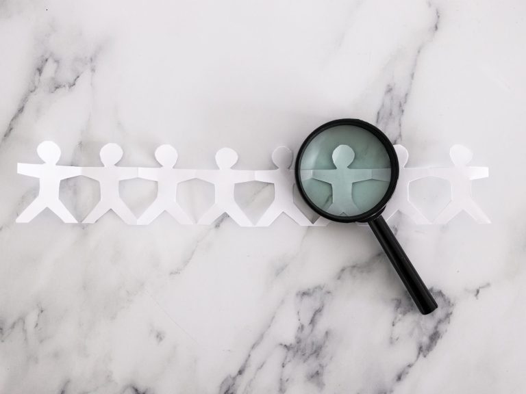 staff shortages and hiring personnel conceptual image, paper people chain with magnifying glass analysing them