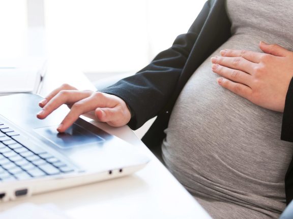 Pregnant woman working on laptop.