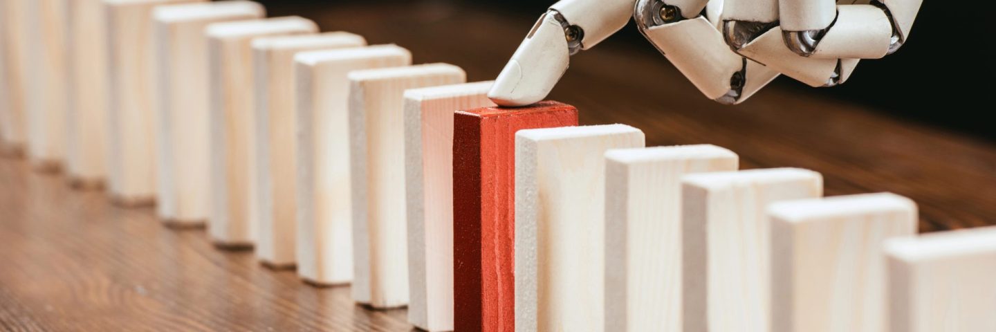 selective focus of robotic hand picking red wooden brick from row of blocks on desk