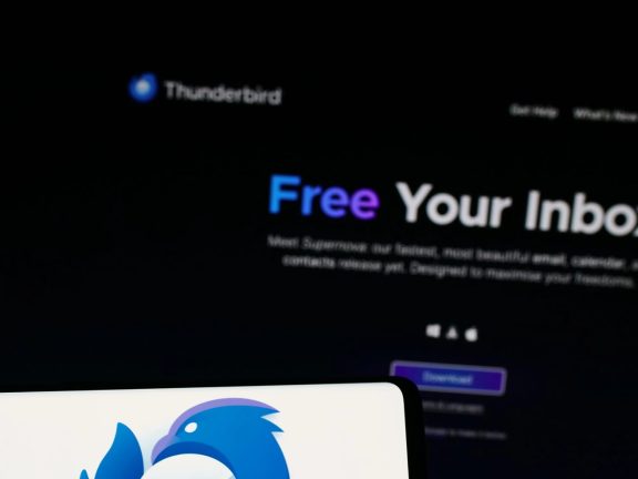 Stuttgart, Germany - 10-25-2023: Person holding mobile phone with logo of open-source e-mail client Mozilla Thunderbird in front of web page. Focus on phone display.