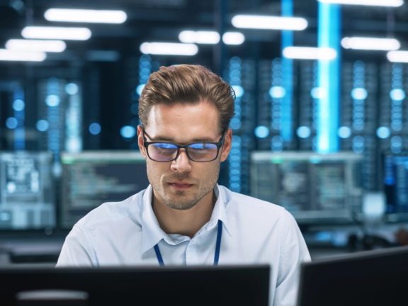 Focused System Administrator or Consultant Look at the Screen and Saves Backup Data in Dark Evening Room Workplace Station Indoors. Network Technologies Concept